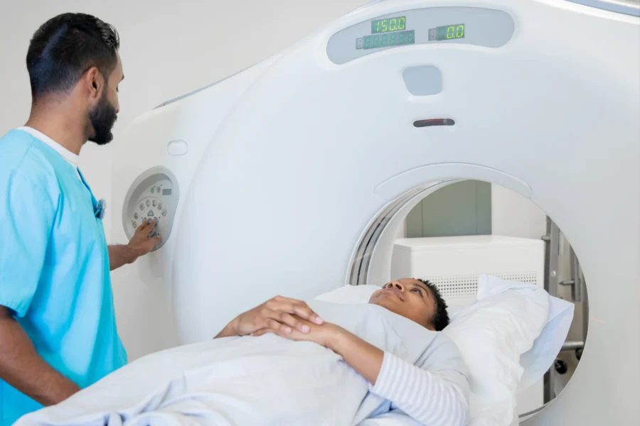 A radiologic technologist operates a CT scanner while a patient lies on the scanning table for a coronary calcium score test.
